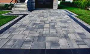 Elegancka ścieżka z kostki granitowej prowadzi do domu. Ciemne obrzeża podkreślają jej urok.
