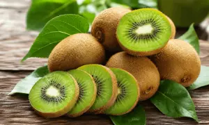 Kiwi frescos, cortados y enteros, sobre madera rústica. Una fuente natural de vitamina K para tu salud.
