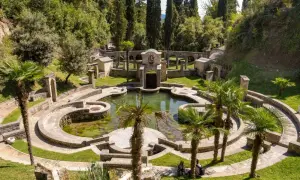 Un incantevole giardino botanico sul Lago di Garda, con un laghetto circondato da architetture in pietra e palme.