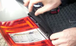 Wymiana żarówki w tyle Seat Ibiza. Dłonie demontują element lampy, przygotowując do wymiany.