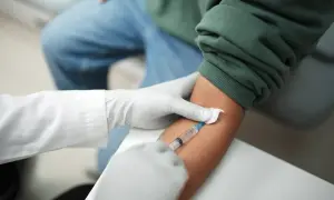 Pobieranie krwi do badań, które mogą pomóc w diagnostyce trzustki. Lekarz w rękawiczkach pobiera krew strzykawką.