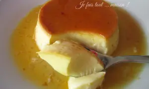 Une cuillère prélève un morceau d'un délicieux crème renversée maison, baignant dans son caramel doré.