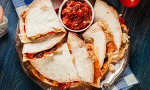 Pyszna quesadilla z kurczakiem, podana z salsą na srebrnej tacy. Idealna na szybki obiad.