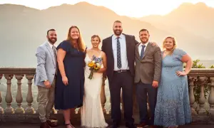 Foto invitati matrimonio: sposi con amici e familiari, con sfondo di montagne al tramonto.