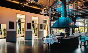 Festsaal Kreuzberg: Ein großer Raum mit Kamin, Tischen und Stühlen, bereit für Gäste.
