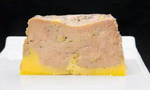 Tranche de pâté en croûte, avec une couche de viande rose et une base jaune, prête pour la cuisson.