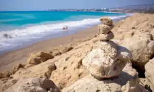 Kamienna wieża na skalistym brzegu, w tle turkusowe morze i piaszczyste plaże Pafos.