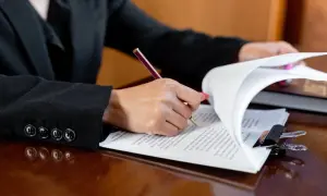 Dłoń podpisuje dokumenty, być może testament. Ważne jest, by pamiętać o zachowku dla najbliższych.