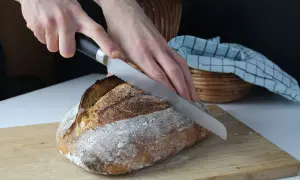 Krojenie świeżego chleba na zakwasie. Idealny chleb na zakwasie przepis to marzenie każdego piekarza.
