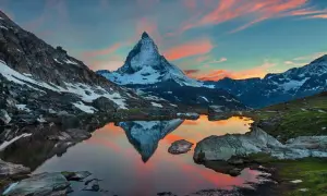 Zachód słońca nad jeziorem z odbiciem Matterhornu. Widok na wejście na Matterhorn, ośnieżone szczyty i malownicze niebo.