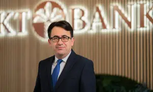 Mann in Anzug vor KT Bank Logo. Positive KT Bank Erfahrung durch professionelles Auftreten.