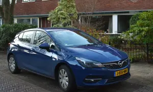 Niebieski Opel Astra K 1.6 CDTI zaparkowany przed domem z cegły.