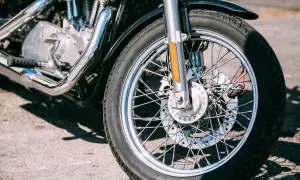 Zbliżenie na przednie koło motocykla z widocznym silnikiem i chromowanymi elementami.