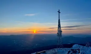Zachód słońca nad Bieszczadami. Krzyż na szczycie, zimowy krajobraz i ławki czekające na turystów. Smerek w tle.