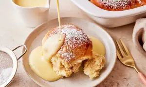 Ein Buchtel wird mit Vanillesauce übergossen, bestäubt mit Puderzucker. Ein köstliches Buchteln Rezept zum Genießen.