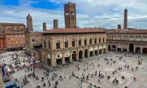 Tłum ludzi na Piazza Maggiore w Bolonii, idealne miejsce na zwiedzanie Bolonii w jeden dzień. W tle widać wieże i zabytkowe budynki.