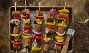 Spiedini di carne succulenti con peperoni, cipolle e zucchine, pronti per essere grigliati.