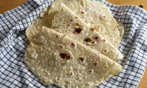 Świeżo upieczone placki na tortilla przepis, ułożone na kratkowanej ściereczce. Idealne do wrapów i quesadilli.