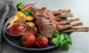 A pyszny comber jagnięcy z pieczonymi ziemniakami, pomidorkami i sosem.