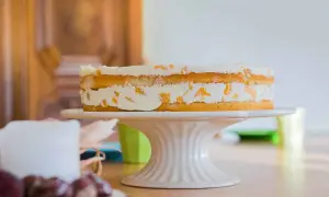 Ein leckerer no bake kuchen mit Sahne und Fruchtstücken auf einem Tortenständer.