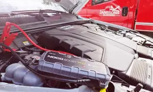 Bil startar inte kallt ute. Startkablar och en batteriboost kopplade till bilens motor.