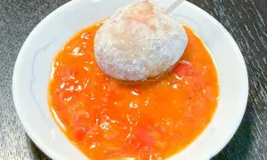 En boll med potatis doppad i en kryddig mojo rojo-sås.
