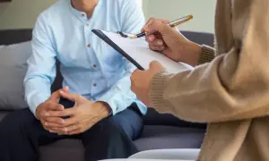Rozmowa z psychiatrą. Pacjent siedzi na kanapie, lekarz notuje na kartce. Kto to jest psychiatra? To specjalista od zdrowia psychicznego.