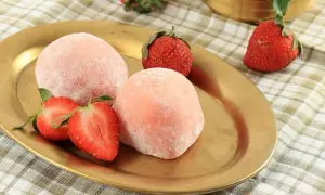 Różowe mochi z truskawkami na złotym talerzu.