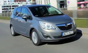 Szary Opel Meriva B w ruchu miejskim, z widocznym kierowcą za kierownicą.