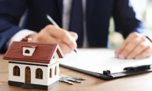 Modellino di casa, chiavi e un uomo che firma un documento. Scopri cos'è la rendita catastale per la tua casa.