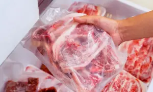 Ręka wyjmuje z zamrażarki paczkę mrożonego mięsa. Dowiedz się, jak rozmrozic mięso, by było gotowe do obiadu.