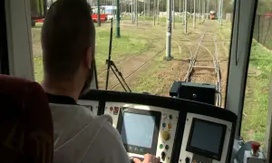 Mężczyzna za sterami tramwaju, być może uczestnik darmowego kursu na maszynistę, obserwuje tory.