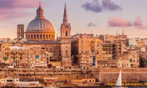 Sonnenuntergang über Valletta, Malta. Die Kuppel der St. Paul's Cathedral und Segelboote spiegeln sich im Wasser. Tolle Urlaub in Malta Erfahrungen!