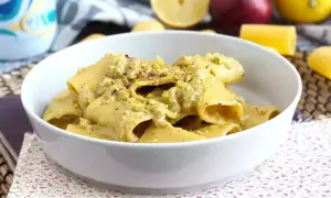 Piatto di pasta tonno e limone, condita con una crema verde e pistacchi tritati, servita in una ciotola bianca.