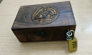 Caja de madera con símbolo celta y candado de combinación, lista para un escape room matematicas.