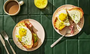 Två läckra croque madame med stekt ägg, ost och skinka, serverade med kaffe och juice.