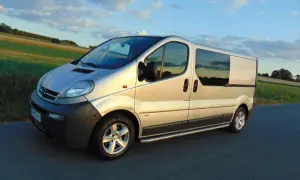 Srebrny Opel Vivaro 2.5 CDTI na drodze, zachód słońca. Wiele osób szuka opinii na forum o tym modelu.