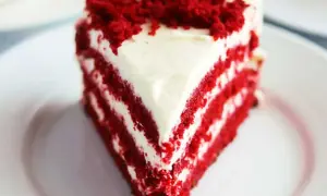 En saftig bit red velvet cake med krämig frosting och smulor på toppen.