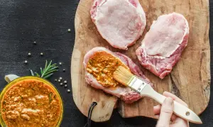 Frisches **Schweinefleisch marinieren** für zarte Steaks. Eine würzige Marinade wird mit einem Pinsel aufgetragen.
