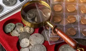Kolekcjonowanie monet to pasja. Starożytne i współczesne monety, szkło powiększające i czerwona aksamitna tacka.