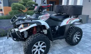 Hyosung TE 450 gotowy na przygodę. Biało-czarny quad z czerwonymi akcentami i bagażnikiem z tyłu.