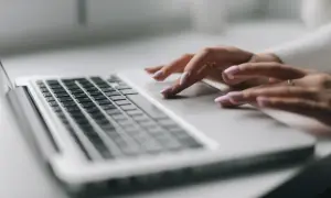 Dłonie z różowym lakierem na paznokciach pracują na touchpadzie laptopa. To nowy model sd-3, który ułatwia codzienne zadania.