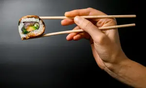Dłoń trzyma pałeczkami jedno sushi. Zobacz, jak jeść sushi, by cieszyć się każdym kęsem!