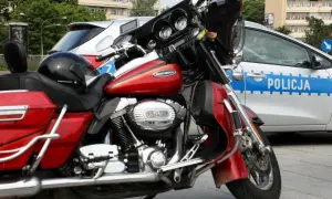 Czerwony motocykl Harley-Davidson obok radiowozu. Czyżby ktoś próbował jeździć bez prawa jazdy?