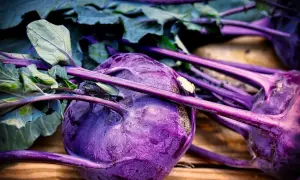 Gros plan sur des choux-raves violets aux feuilles vertes, posés sur du bois. Un légume coloré prêt à être cuisiné.