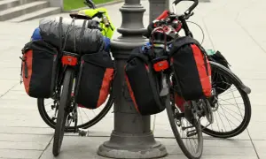 Dwa rowery z sakwami i bagażami, gotowe do wyprawy. Widać śpiwór, kask i inne rzeczy, które warto zabrać na wyprawę rowerową.