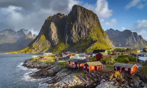 Traumhafte norwegen route 2 wochen: Rote Fischerhäuser am Fuße steiler Berge an der Küste.