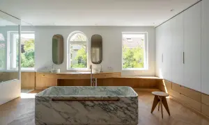 Baño moderno con bañera de mármol, lavabos y armarios de madera. Un ejemplo de reformas casas de pueblo con estilo.