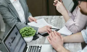 Persone riunite attorno a un tavolo per discutere documenti. Il garante deve essere presente al rogito.