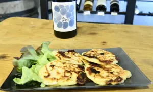 Assiette de migliacci dorés, accompagnés de salade verte, avec une bouteille de vin en arrière-plan. Une recette simple et savoureuse.